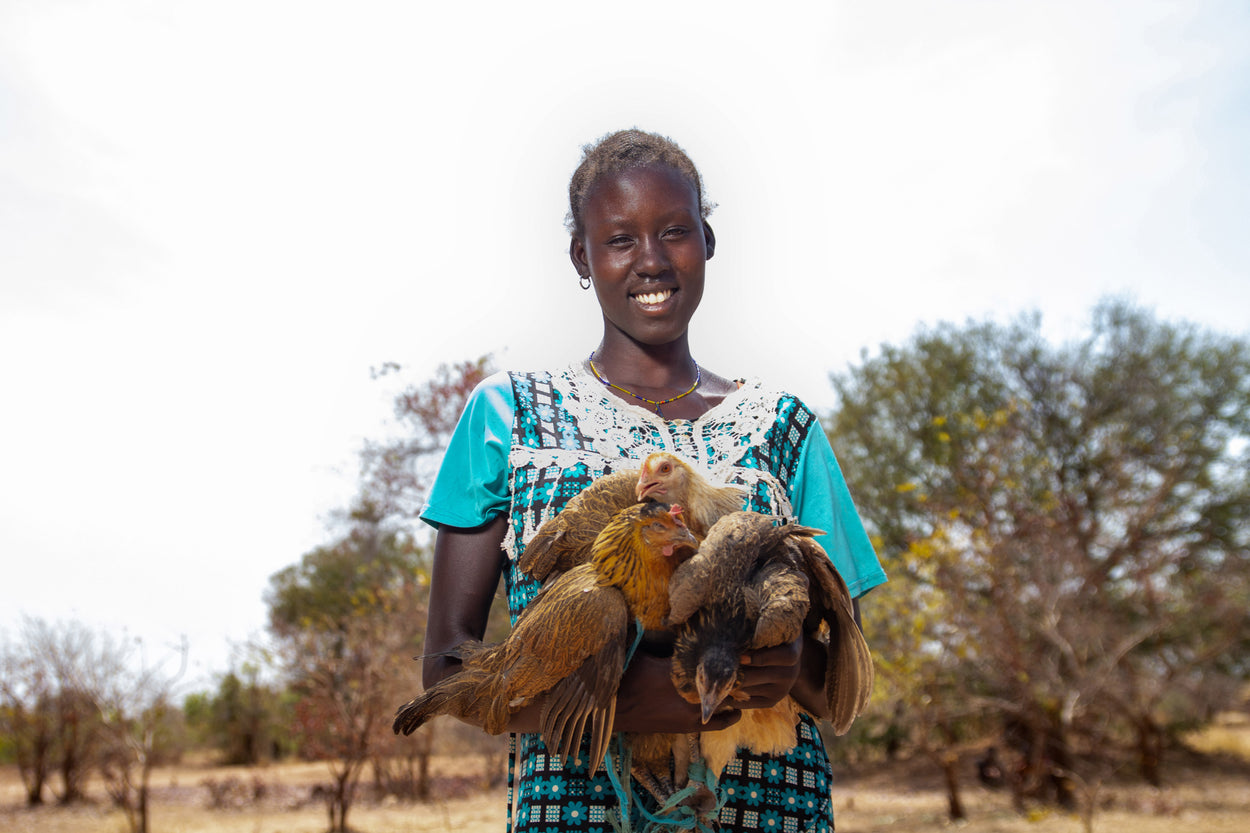 Ampu Luol smiles as she holds her chickens she received from World Concern.