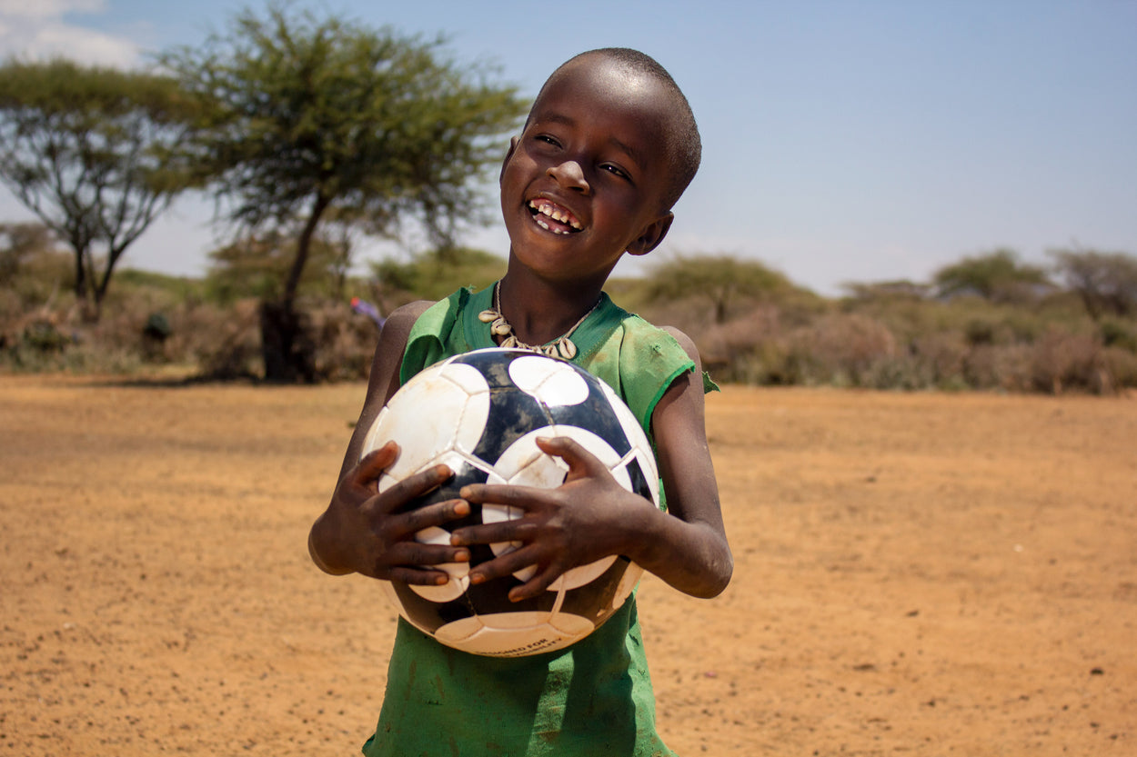 A girl smiles as she holds her soccer ball.