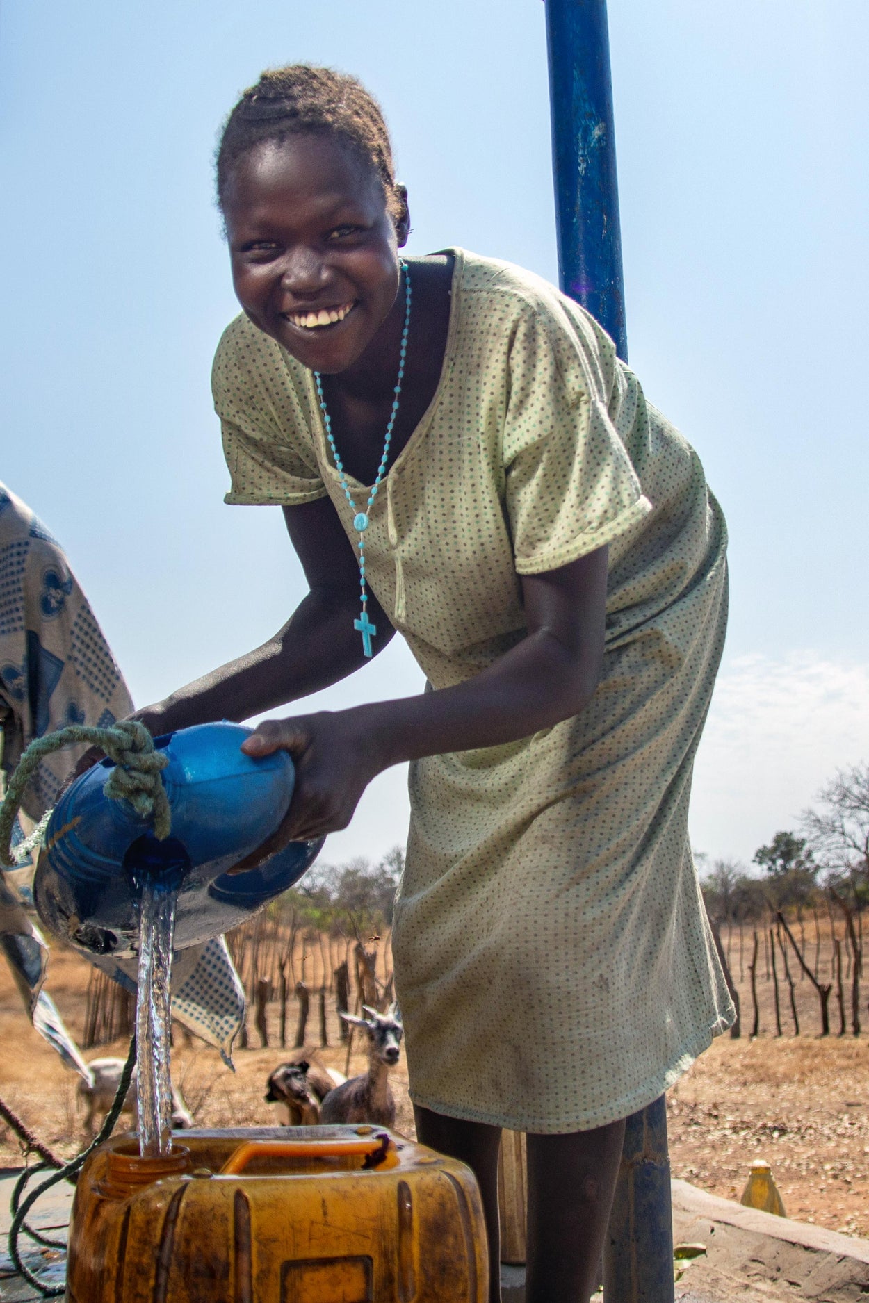 A woman smiles as she draws clean water from a well!