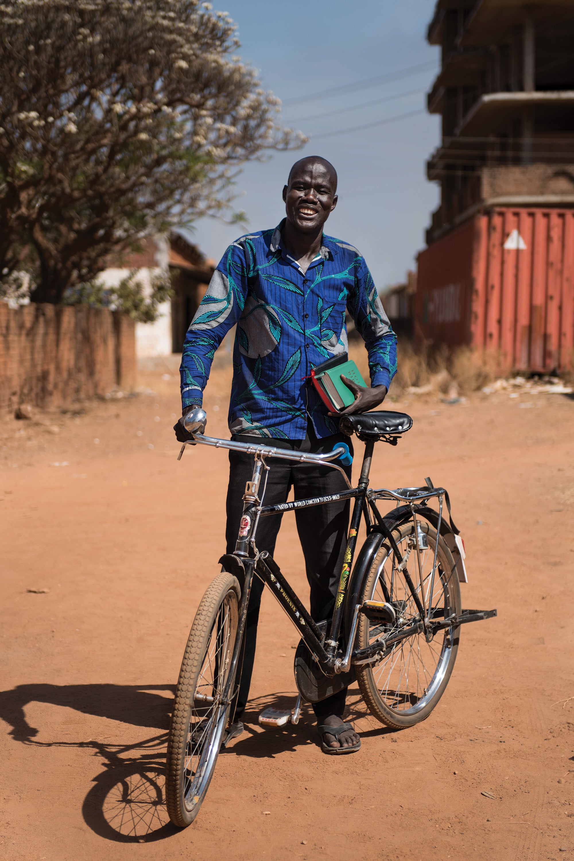 An evangelist stands with his bicycle and a bible.