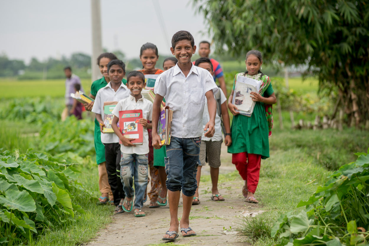 a boy holding a book walking in front of a group of children