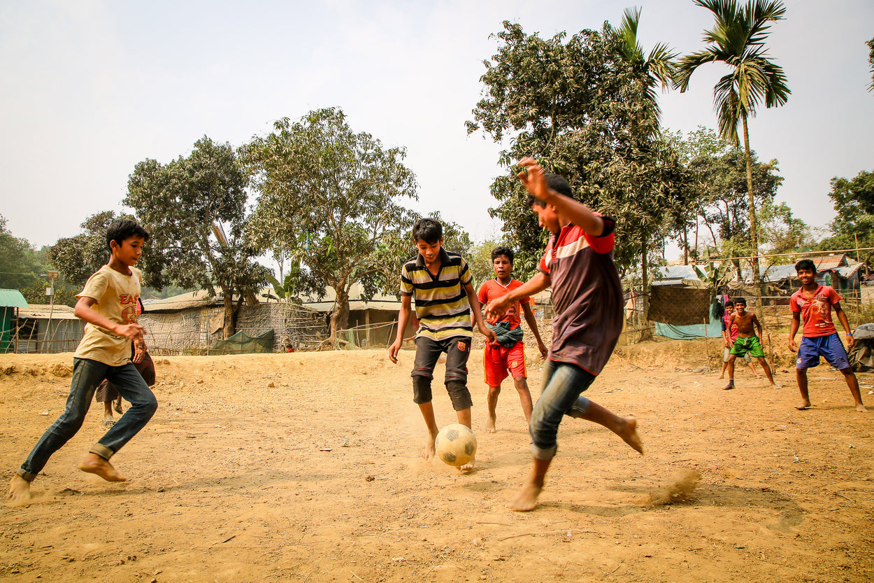 a group of boys playing soccer in the sand