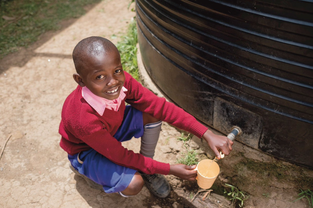 A boy collects clean water from a rainwater collection tank.