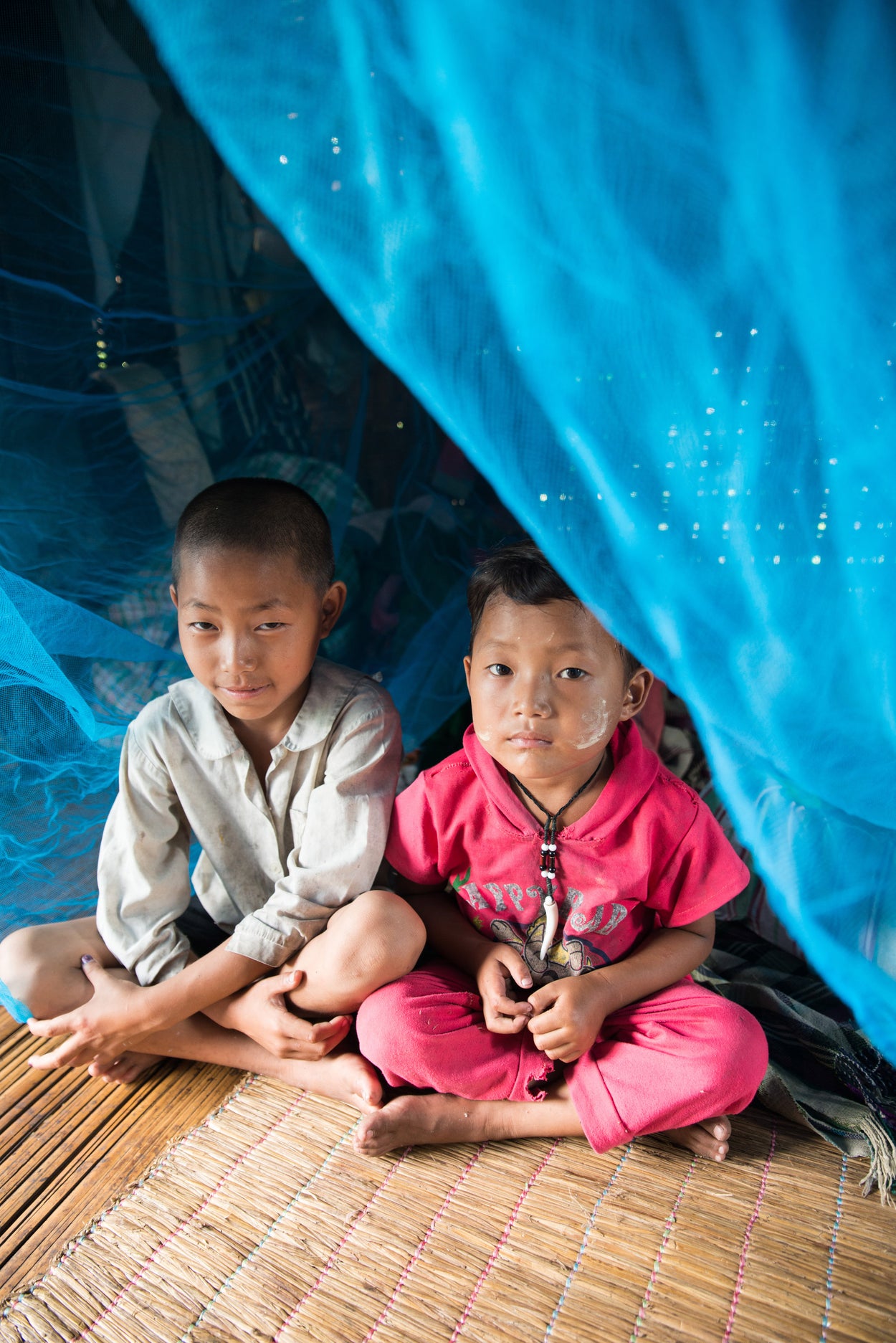 two children sitting under a mosquito net 