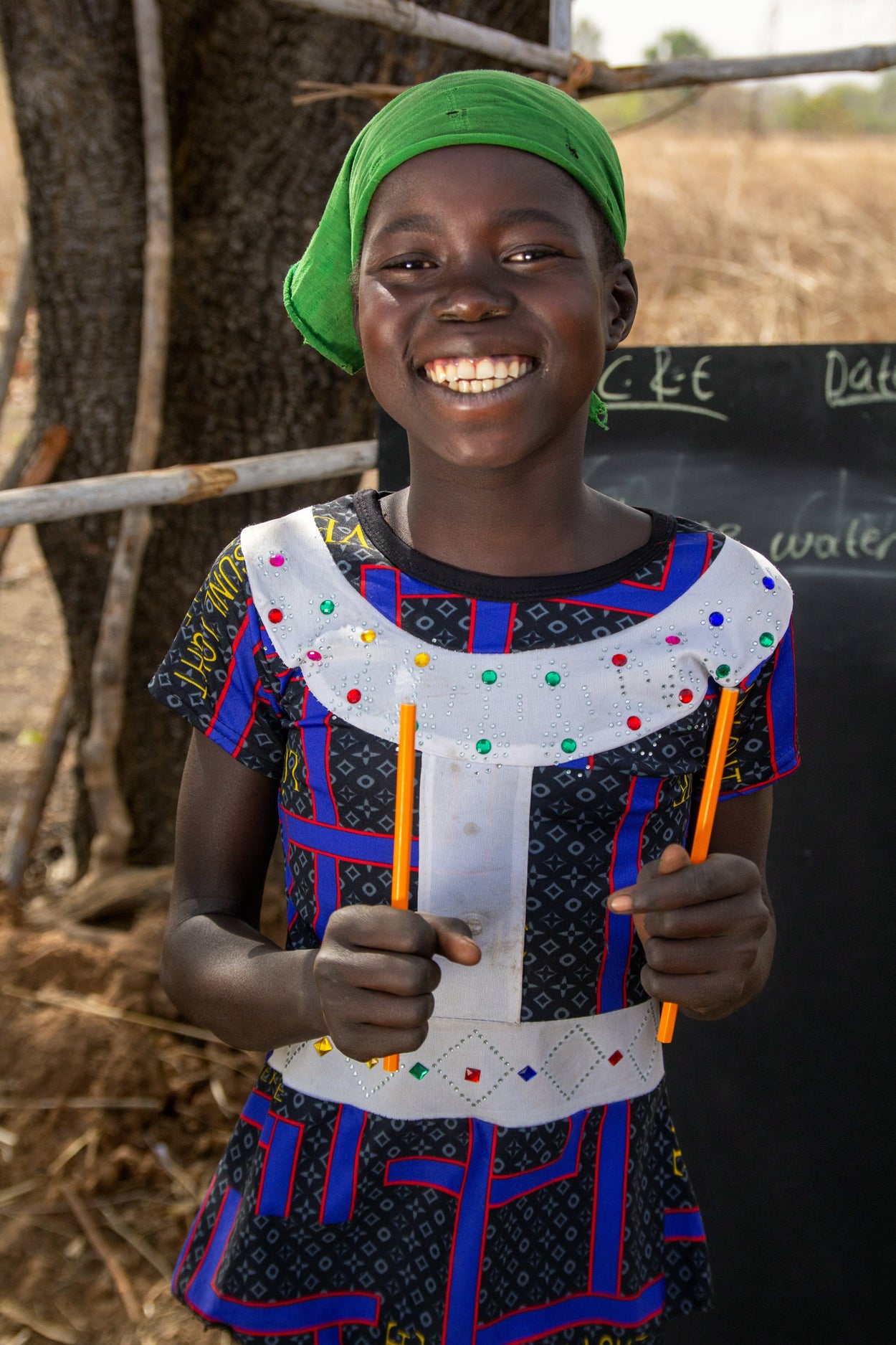 A smiling girl holds shows off her new pencils. 