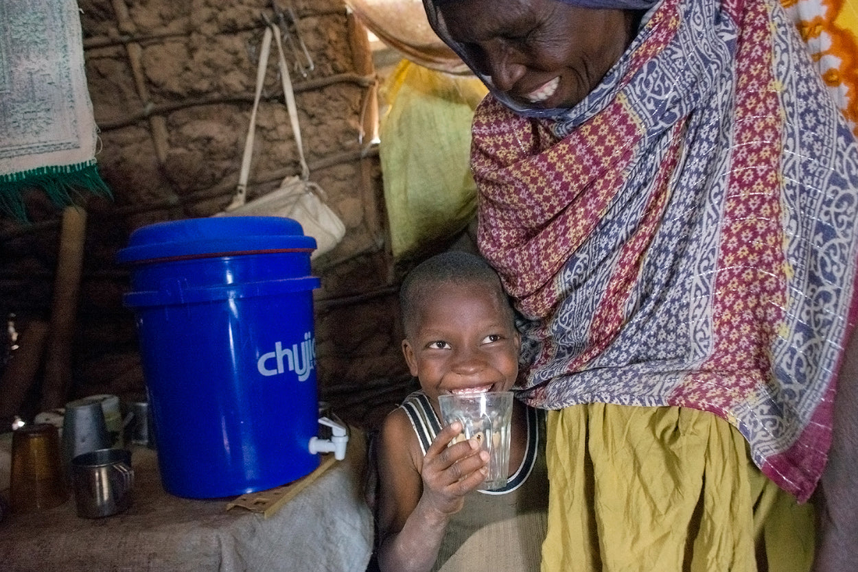 A happy boy drinks clean water from his water filter.