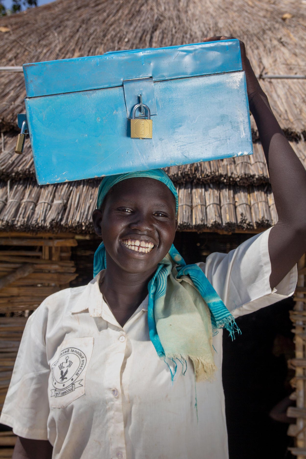 Madil holds a savings group kit, it includes a cashbox, lock, passbooks, and a ledger!