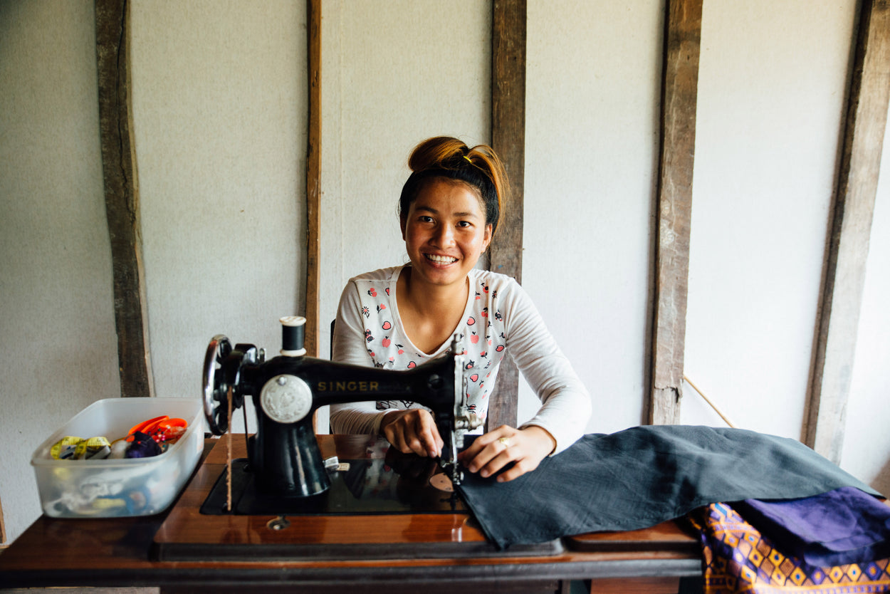 woman sitting behind a sewing machine on a table