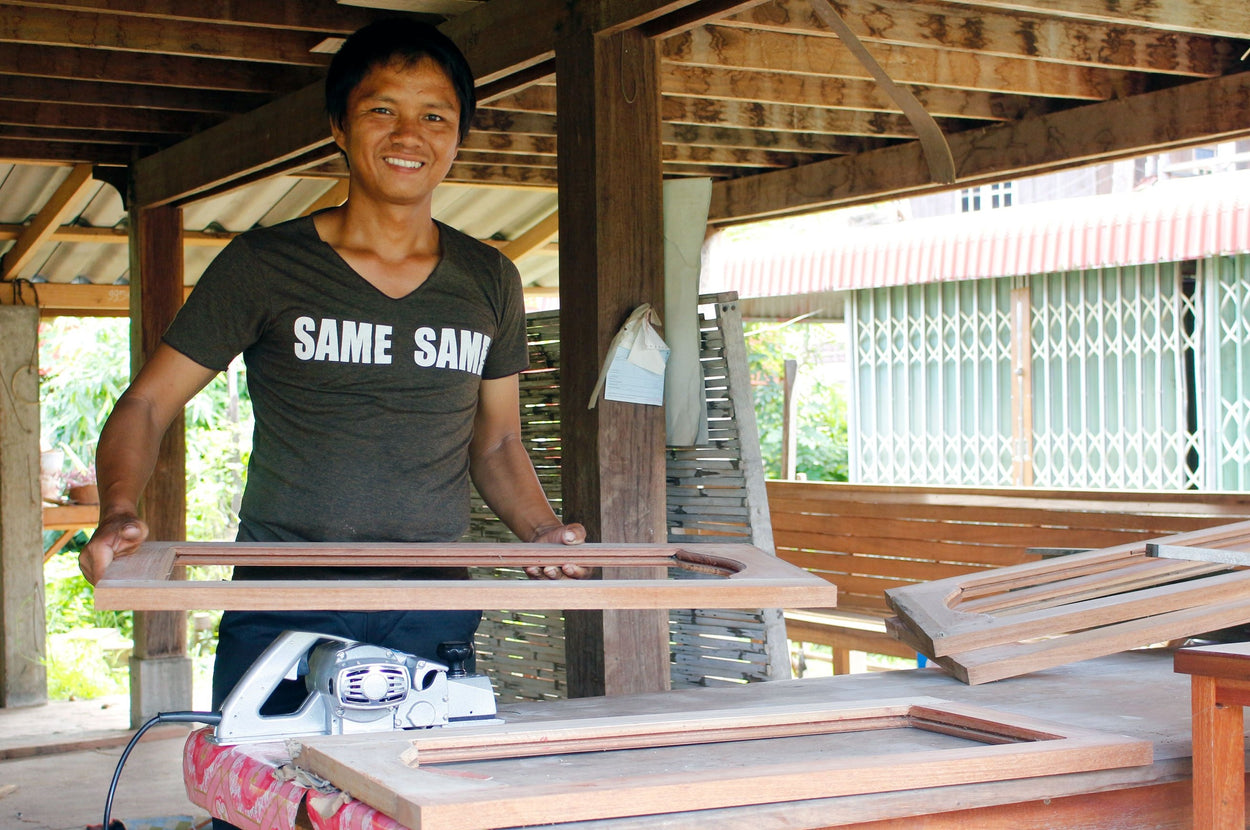 A man shows of the windows he's made from the woodworking skills he's learned.