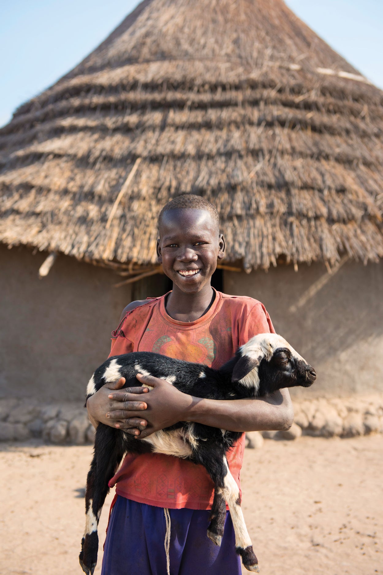 A boy in South Sudan holds a goat.