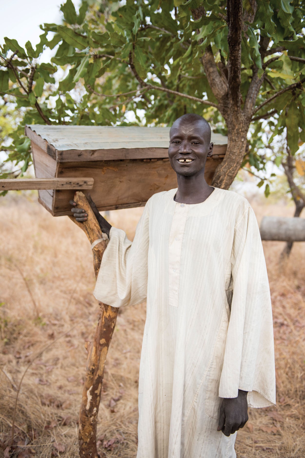 A man smiles as he stands in front of his honey bees!